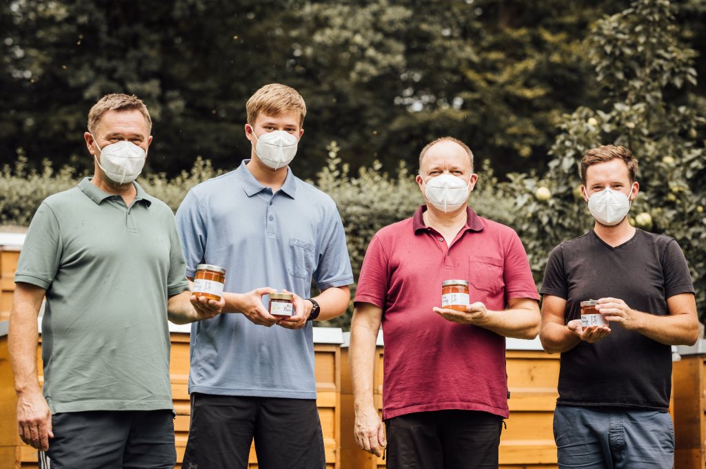 Vier Landwirte mit einem Glas Honig in den Händen