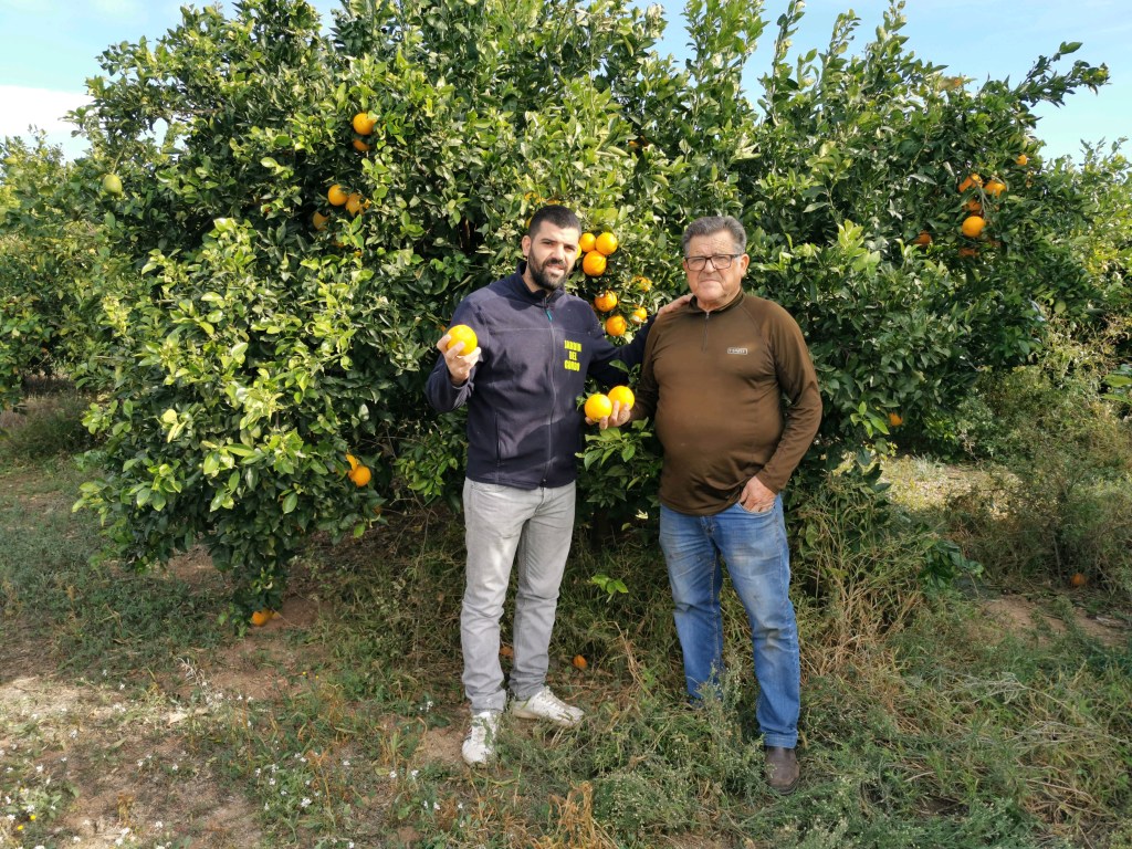 Farmer Sergio Mu&ntilde;oz and his father posing in front of his orange farm