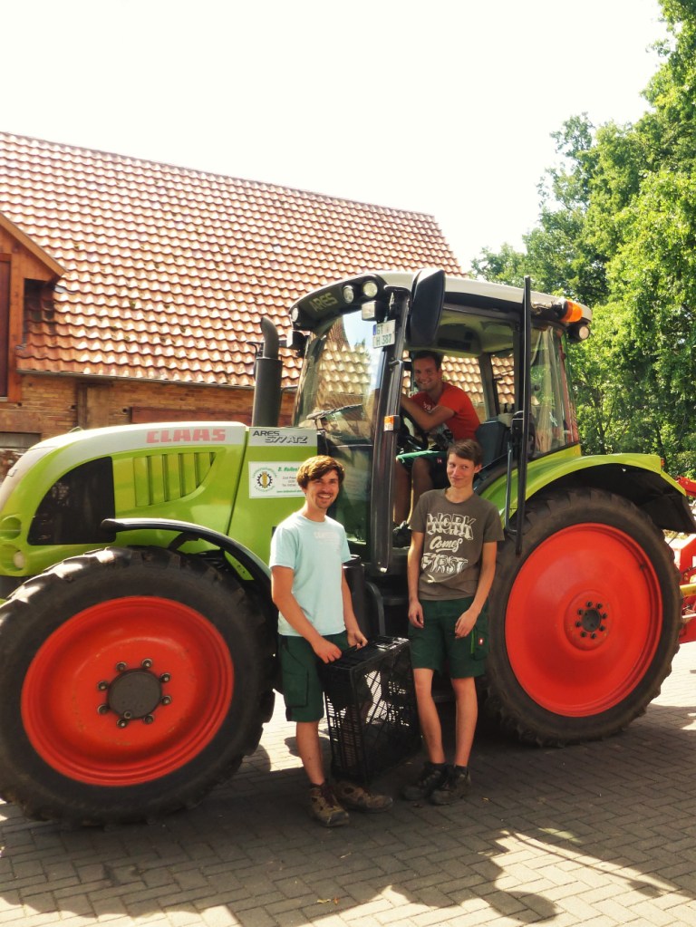 3 farmers in front of a tractor